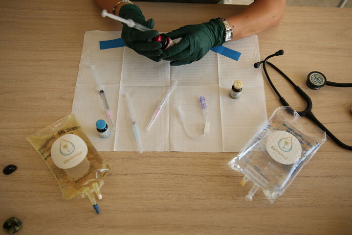 Gloved hands preparing injection supplies on a table beside a stethoscope