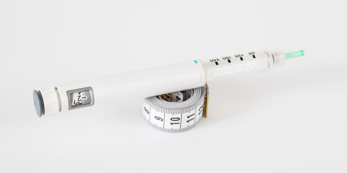 Weekly injection pen resting on a measuring tape